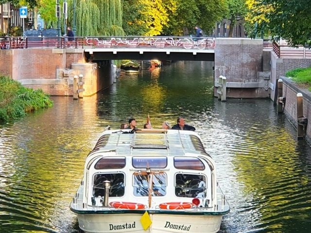 Domstad Stadsbuitengracht a boat floating along a river next to a body of water