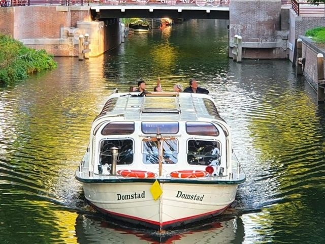 a boat floating along a river next to a body of water