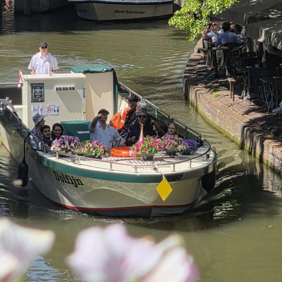 Boat with people passing under a bridge on a sunny canal.