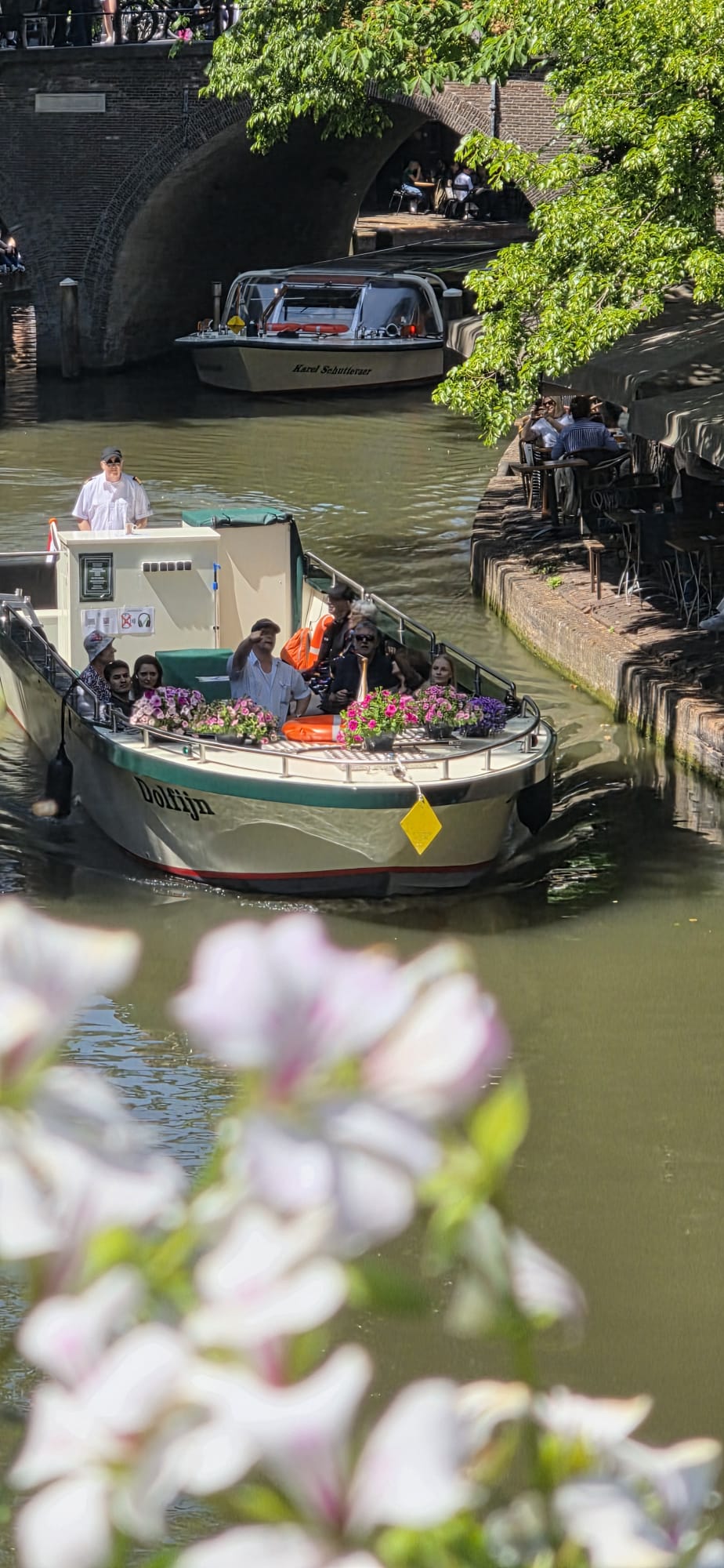 Boat with people passing under a bridge on a sunny canal.