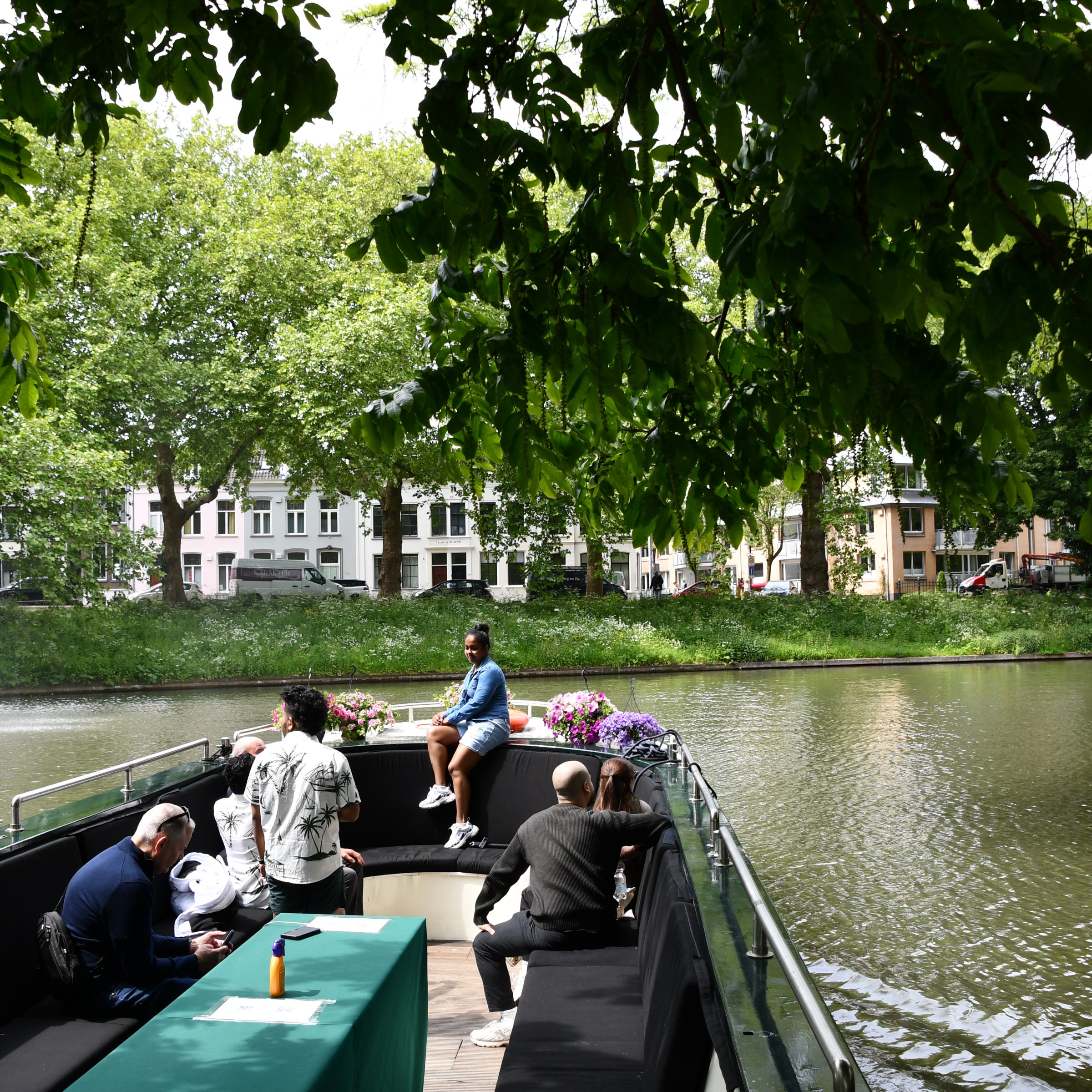 People sitting on a boat in a park with trees and a pond.