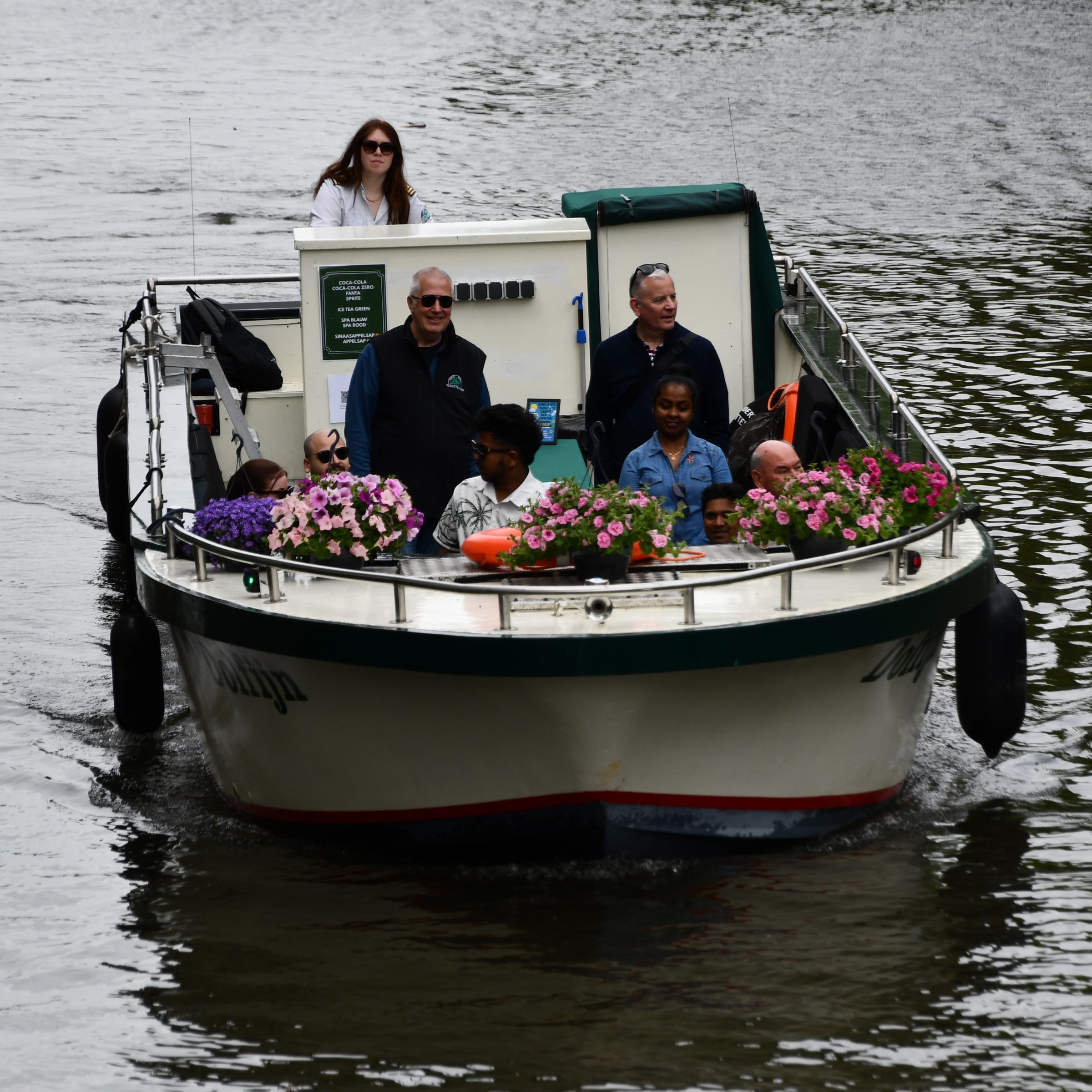 People on a small boat decorated with flowers on a river.
