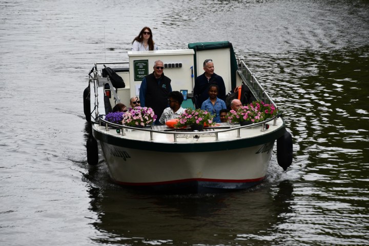 People on a small boat decorated with flowers on a river.
