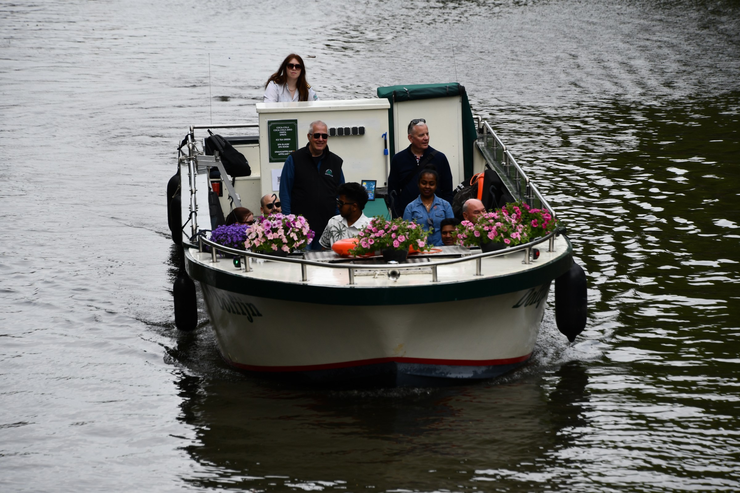 People on a small boat decorated with flowers on a river.