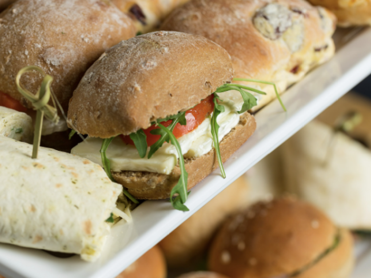 Tray of assorted sandwiches with various fillings including lettuce and tomato.