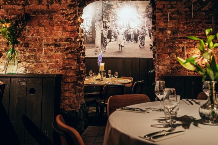 Rustic restaurant interior with exposed brick walls, elegant table settings, and vintage black-and-white photo.