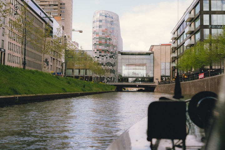 Modern buildings and canal view from a boat under a bridge.
