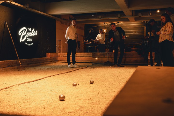 People playing boules indoors with dim lighting.