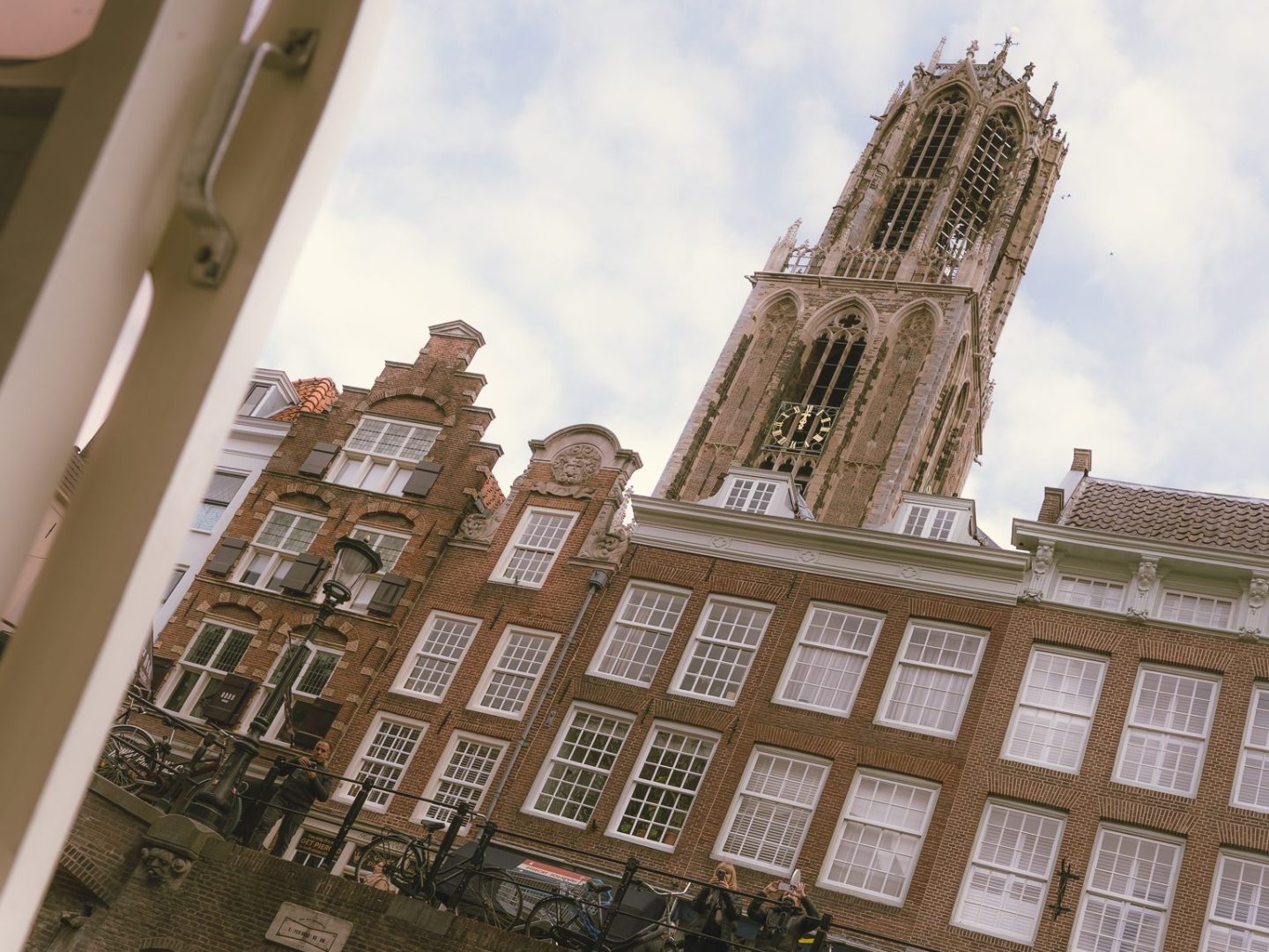 Tilted view of historic buildings and a tall tower under a cloudy sky.