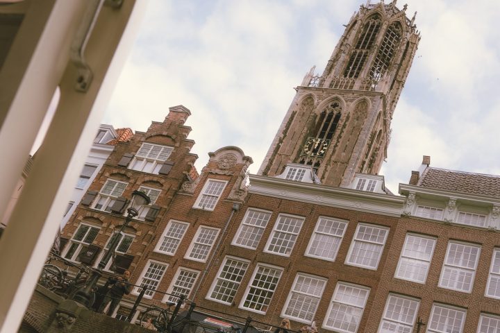 Tilted view of historic buildings and a tall tower under a cloudy sky.
