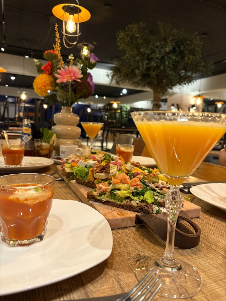 Cocktail glasses and shared platter on a restaurant table with floral centerpiece.