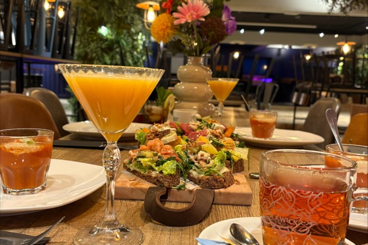 Restaurant table with drinks, salad, and floral centerpiece.