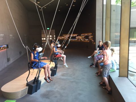 People in a modern room using VR headsets on swing-like seats.