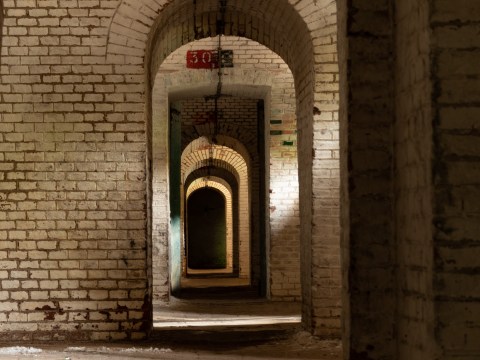 Series of arched brick doorways receding into darkness.