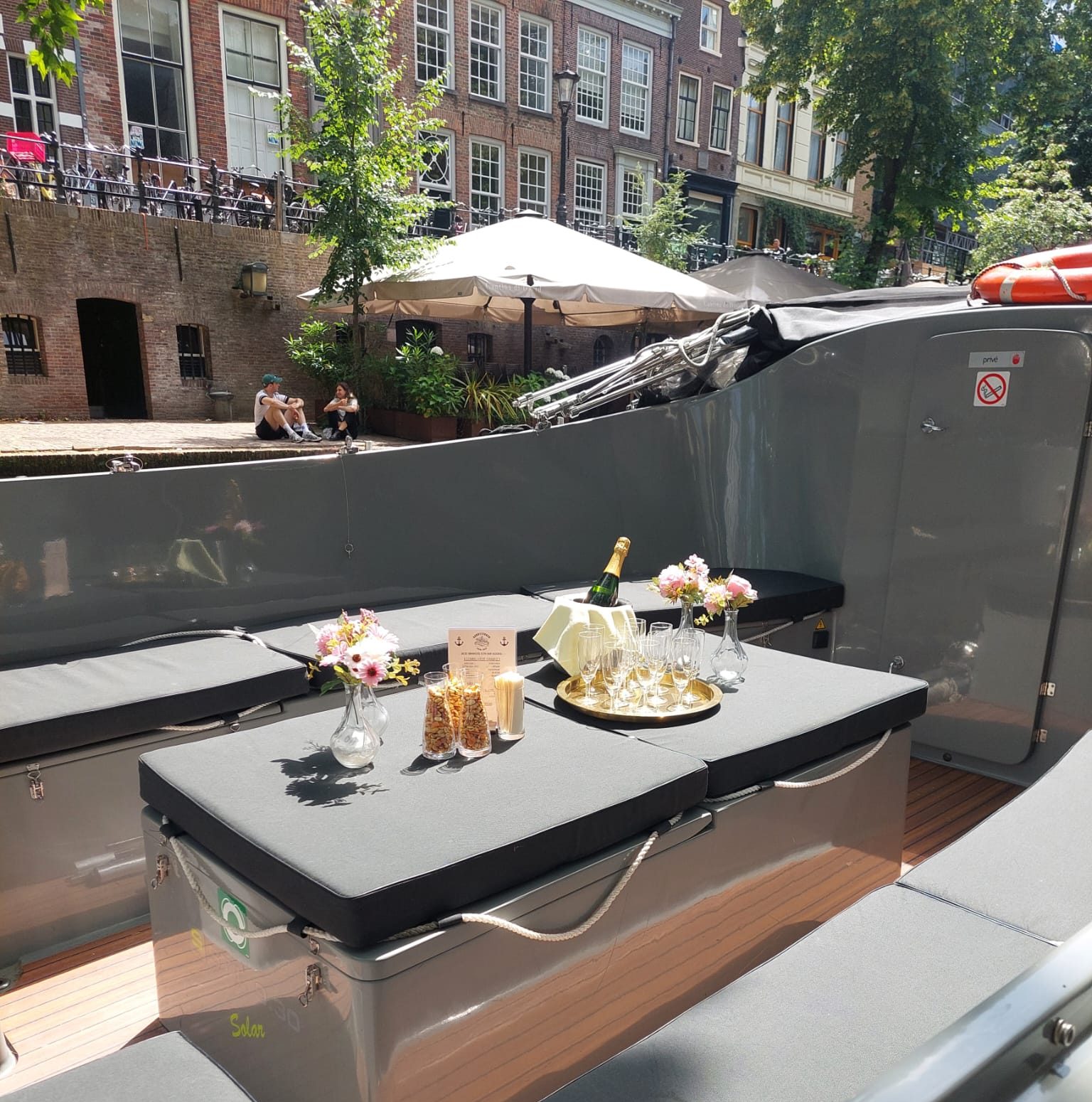 Outdoor boat seating with champagne, flowers, and snacks.