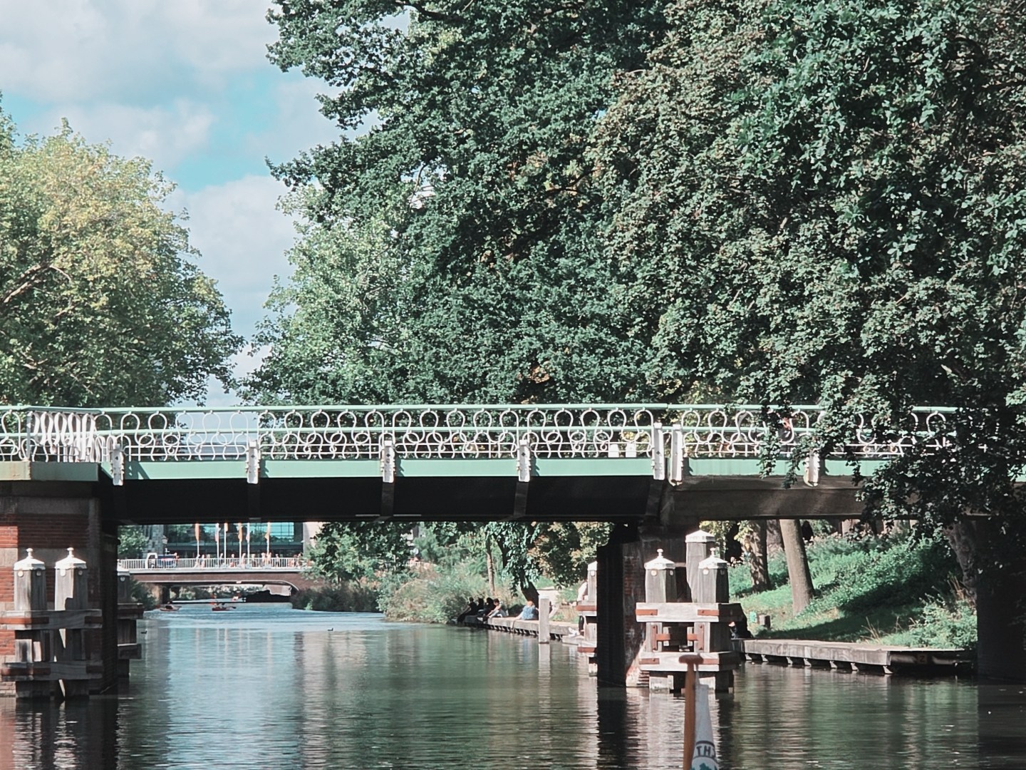 Bridge over a canal with trees and orange lifebuoy rings.